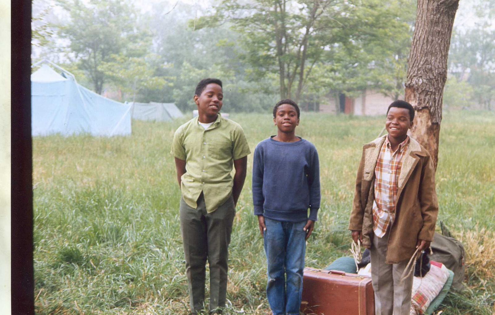 Three scouts standing in a field at camp