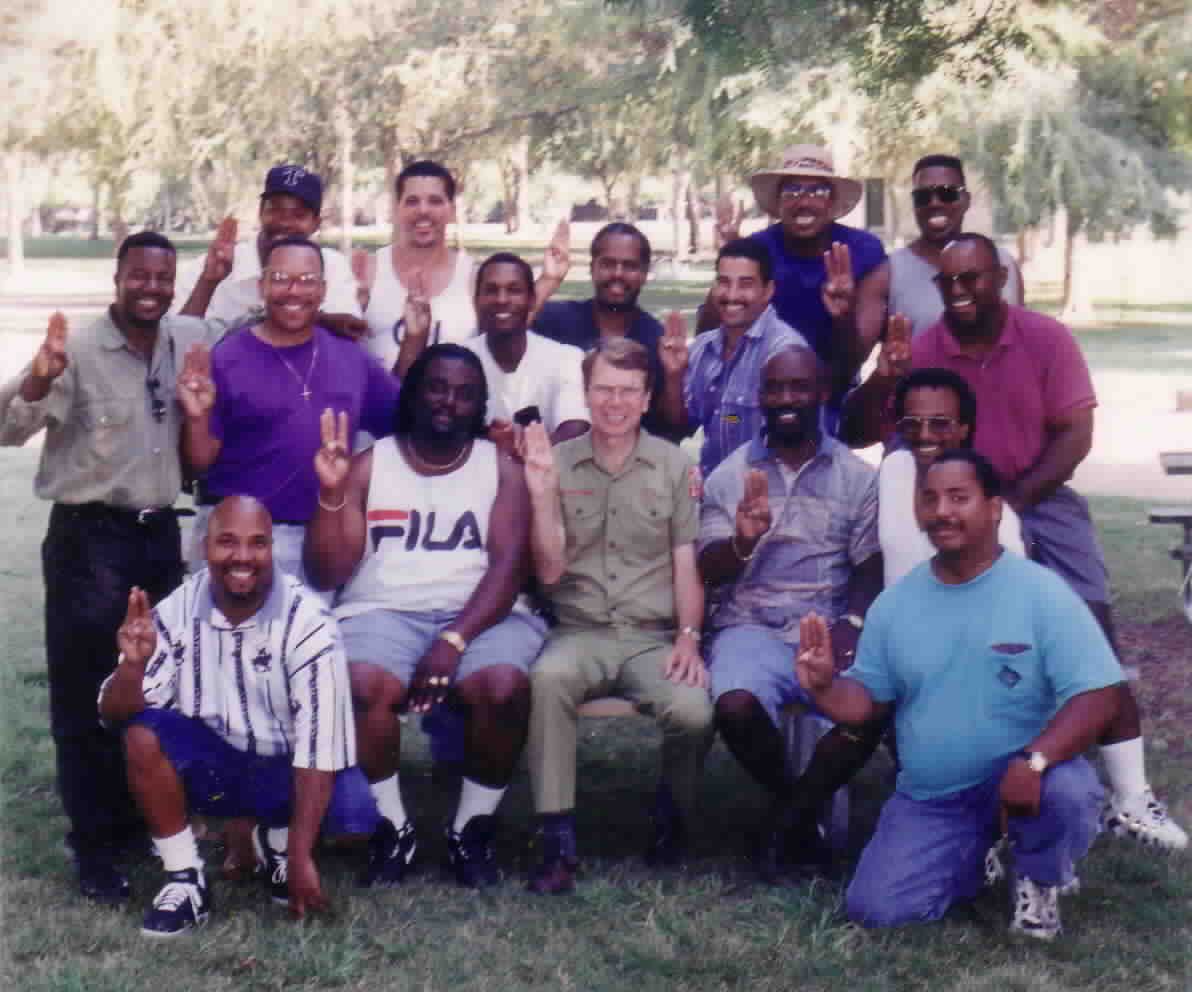 Grown former scouts, many giving the Scout sign, at a reunion