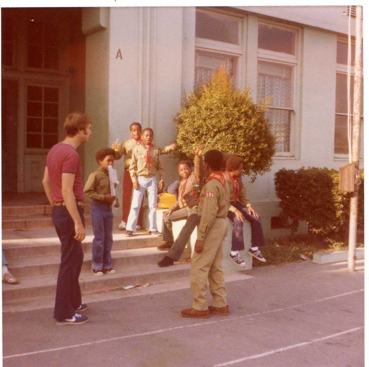 Scouts and young men on the front steps of a school building